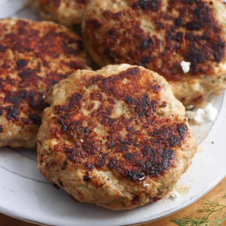 greek chicken burger patties on a white plate.