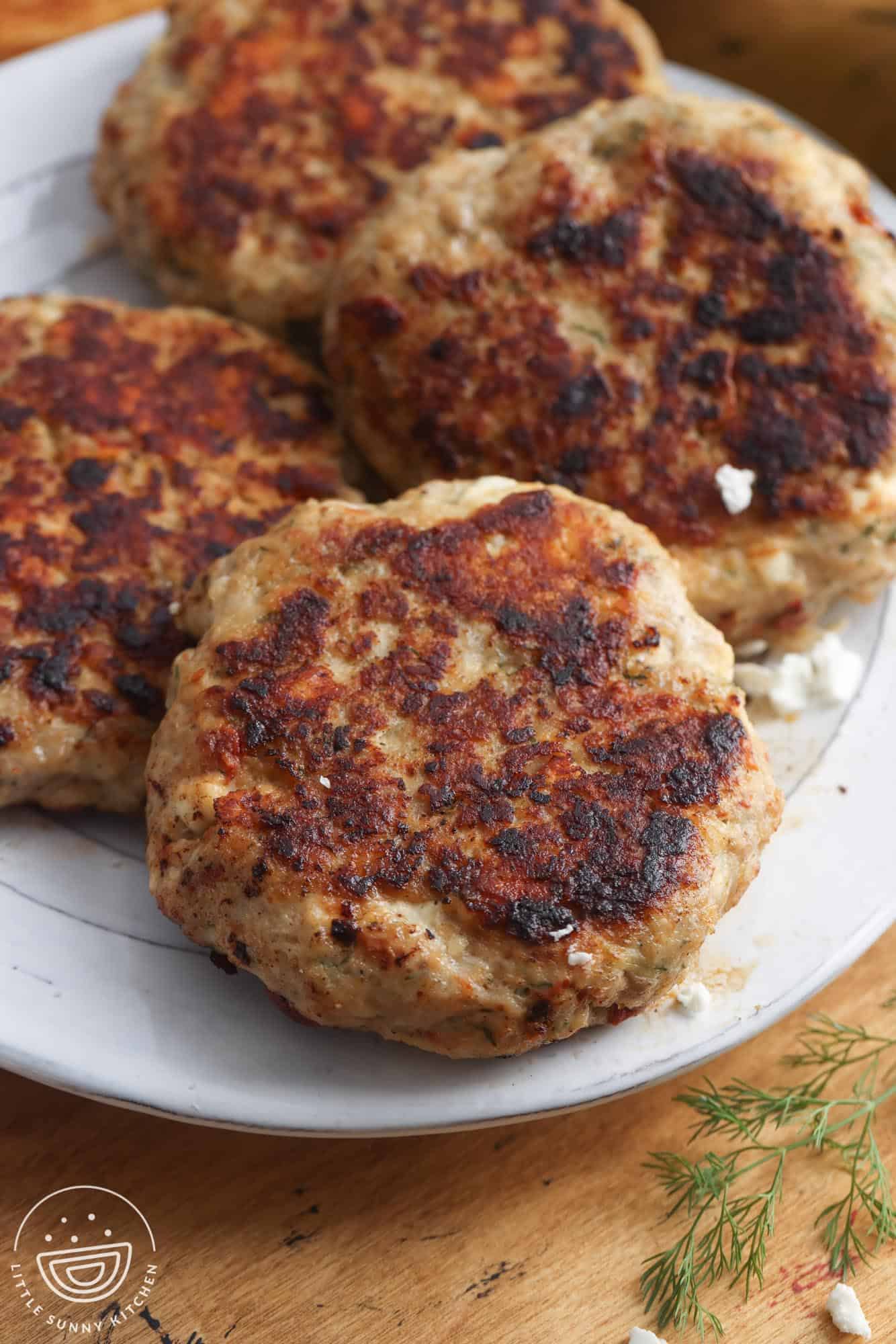 greek chicken burger patties on a white plate.