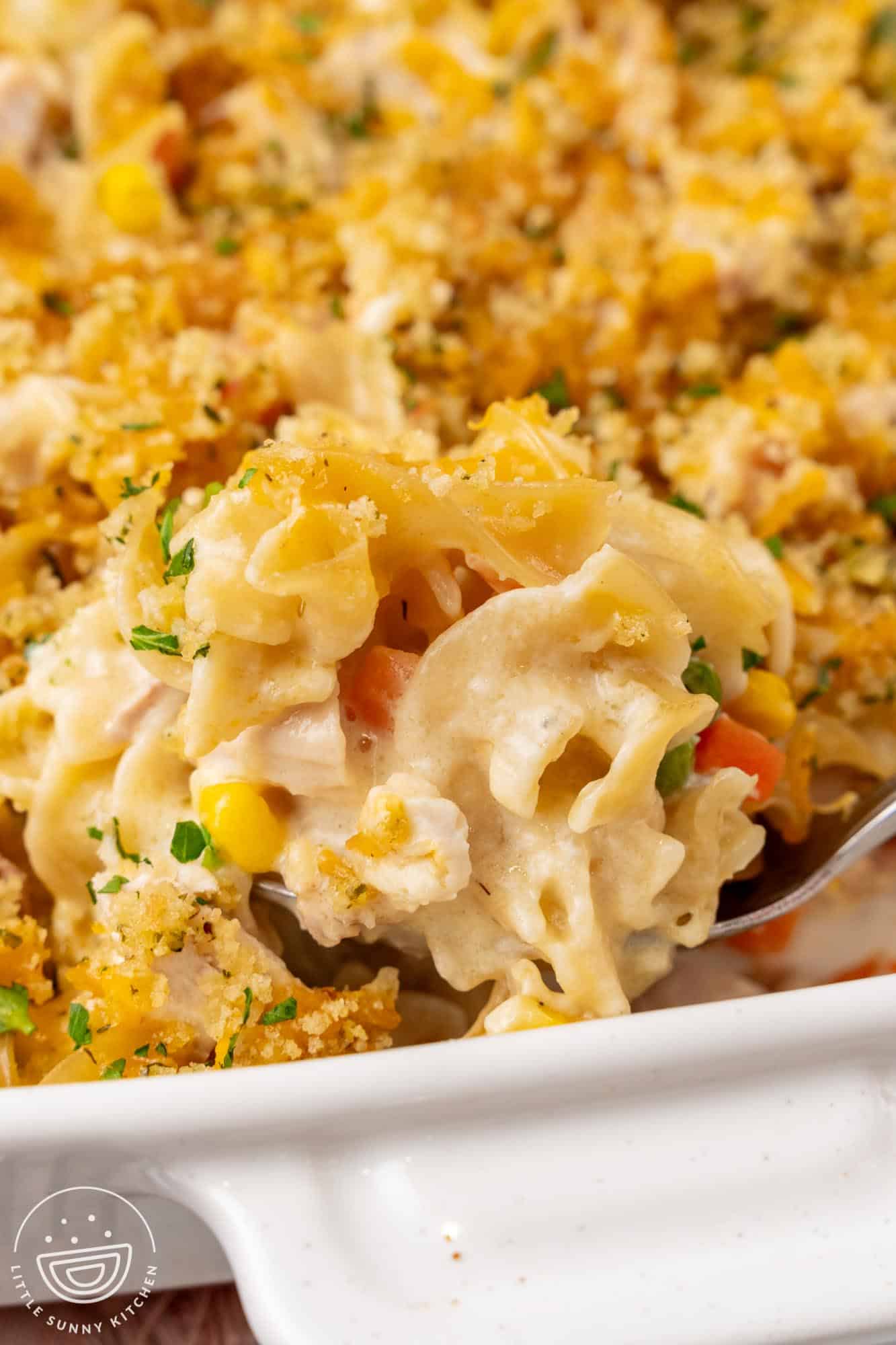 Closeup of a spoonful of chicken noodle casserole showing egg noodles in a creamy sauce with vegetables.