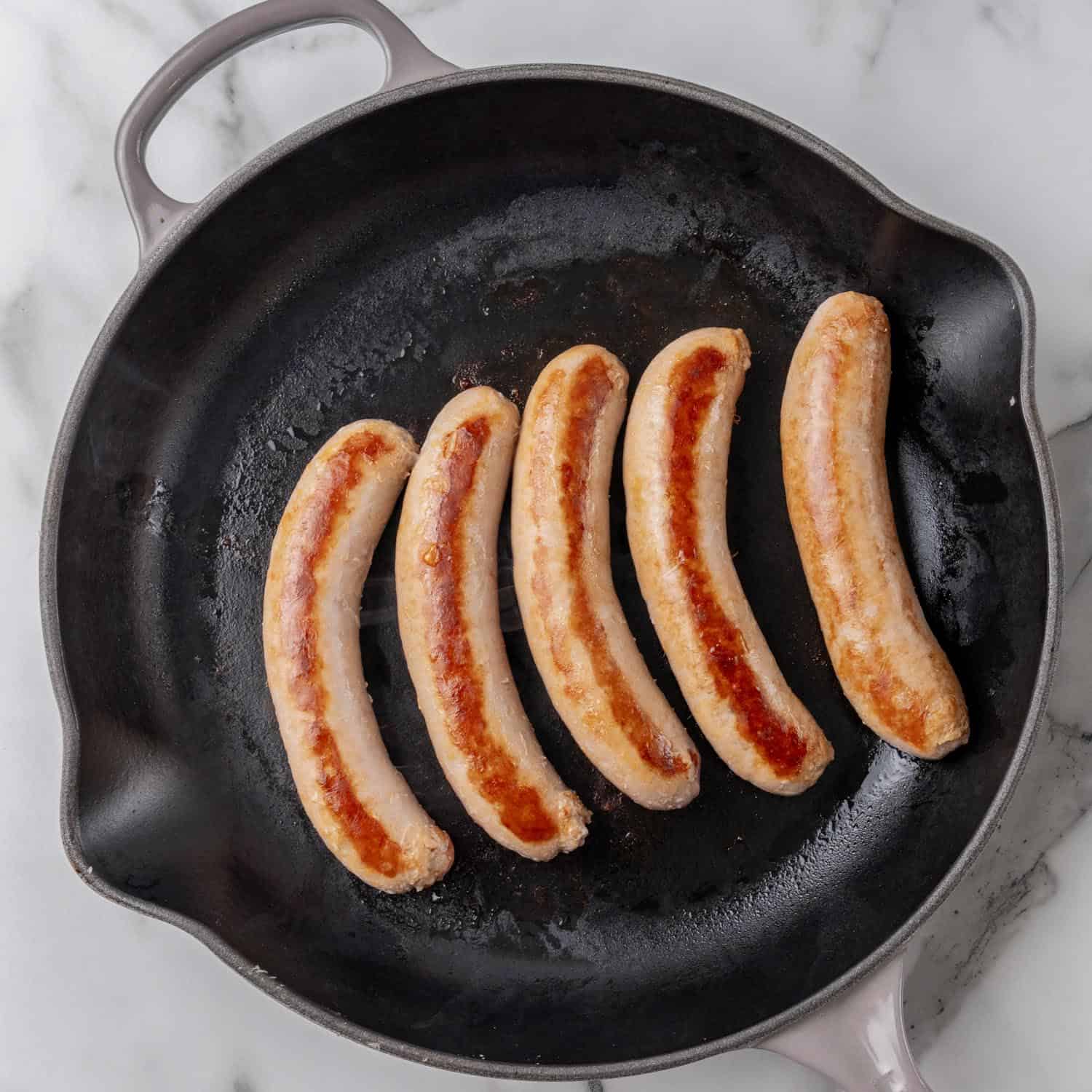 5 italian sausage links, browning in a cast iron skillet.