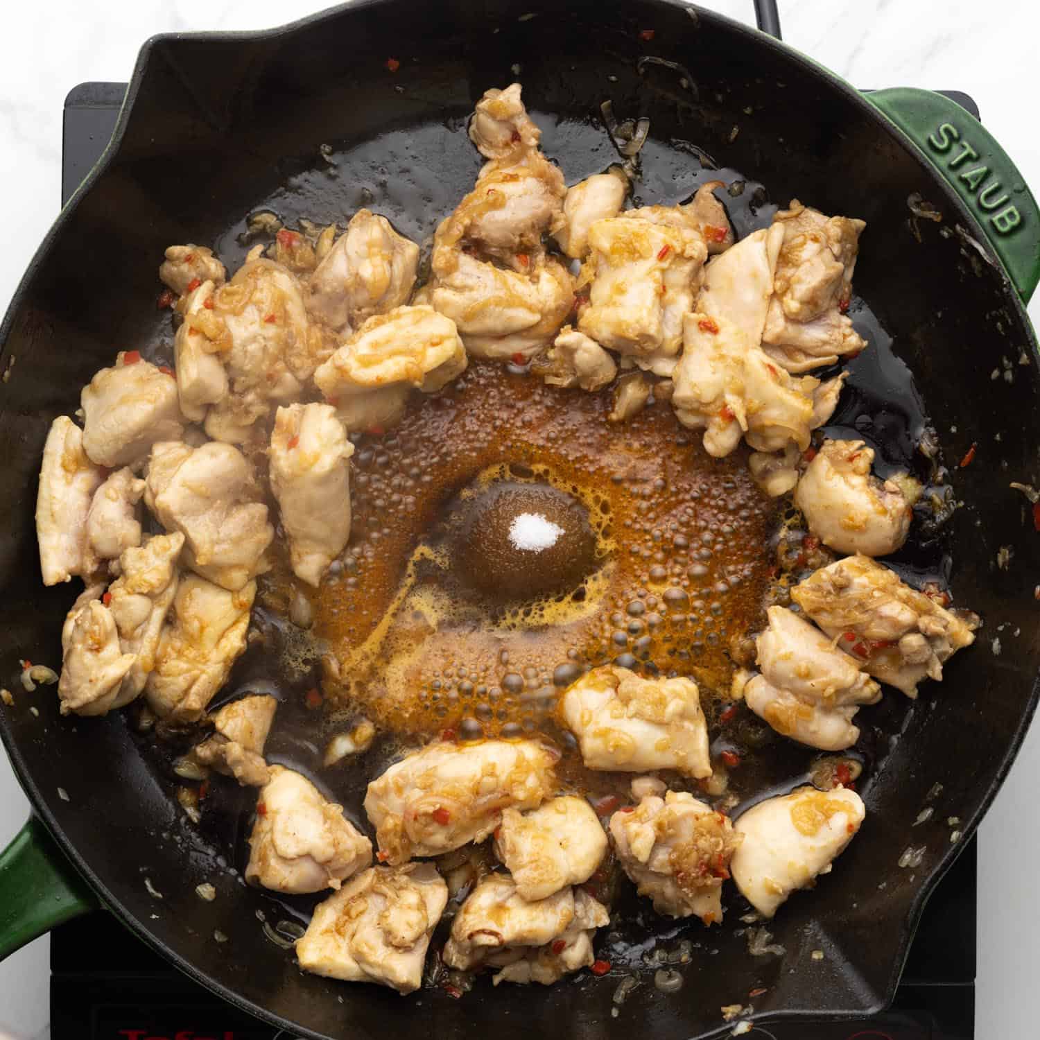 Soy sauce, fish sauce, and sugar added to a skillet of cooked chicken.