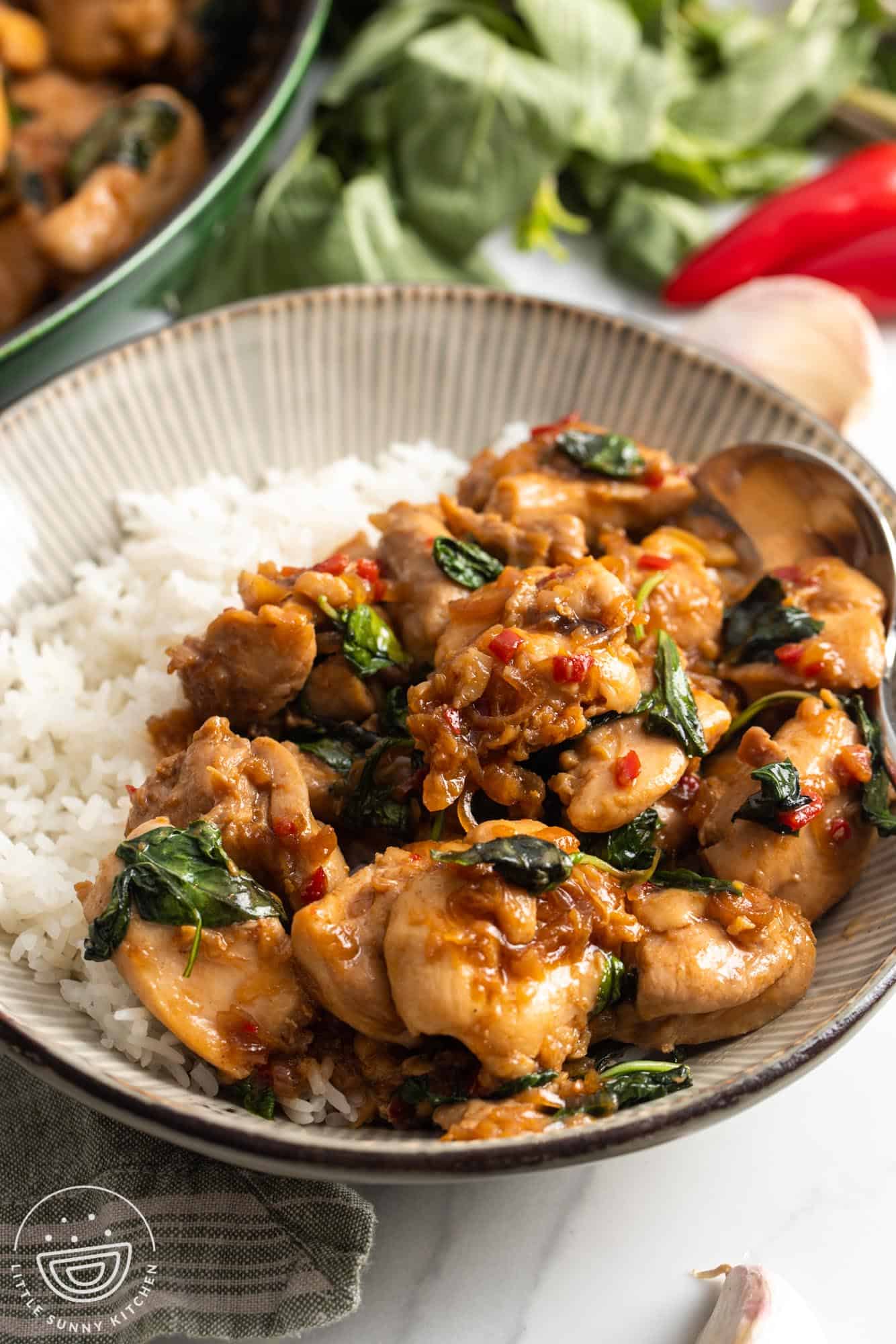 Thai basil chicken with chili peppers in a bowl with rice.