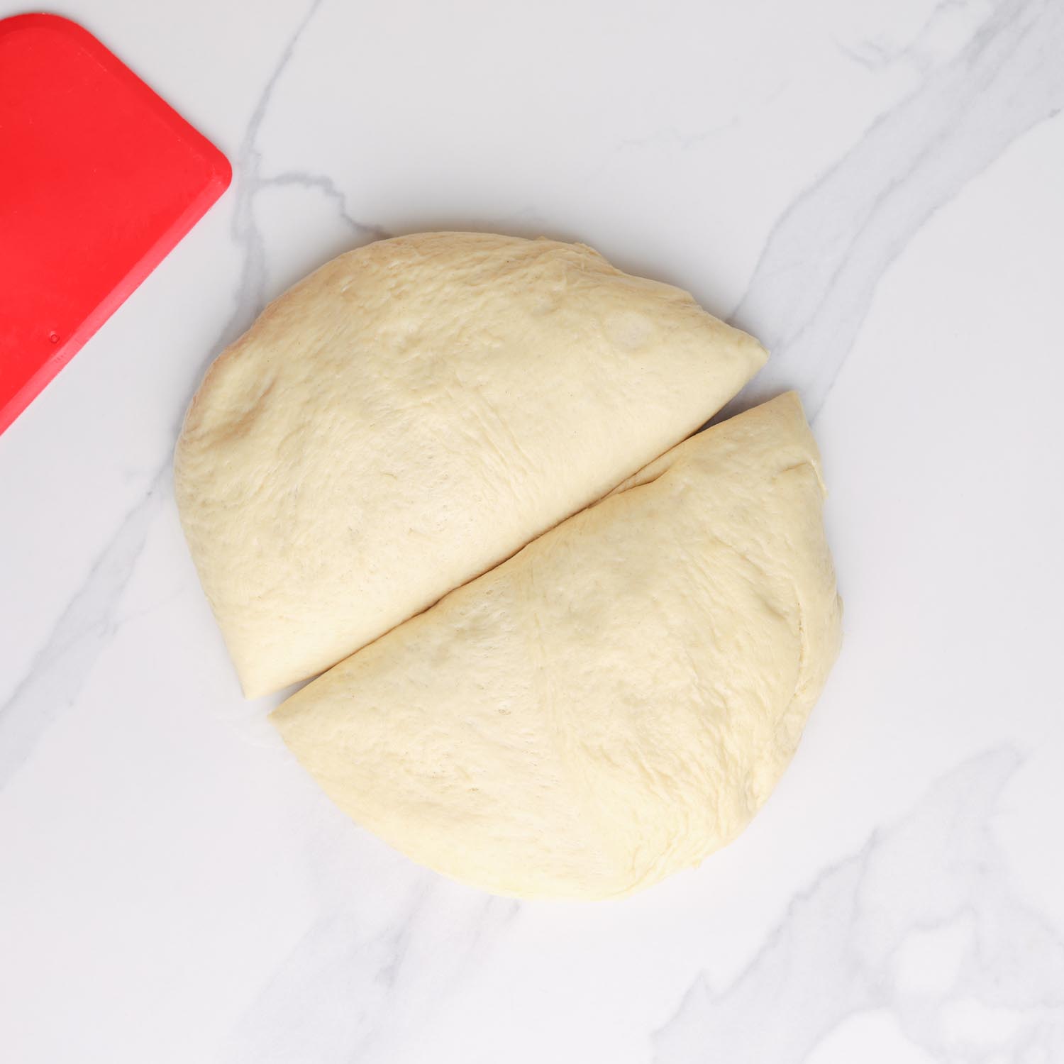 pide dough after rising, cut into two equal portions on a marble counter. 