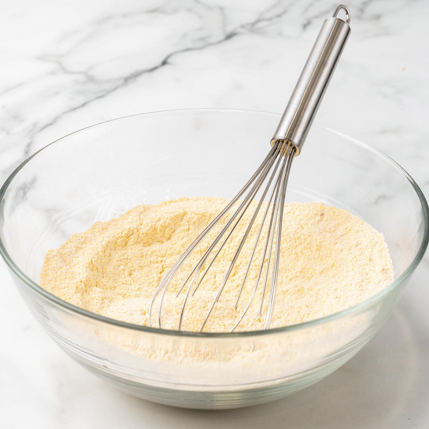 cornmeal, flour, and baking powder whisked in a glass bowl.