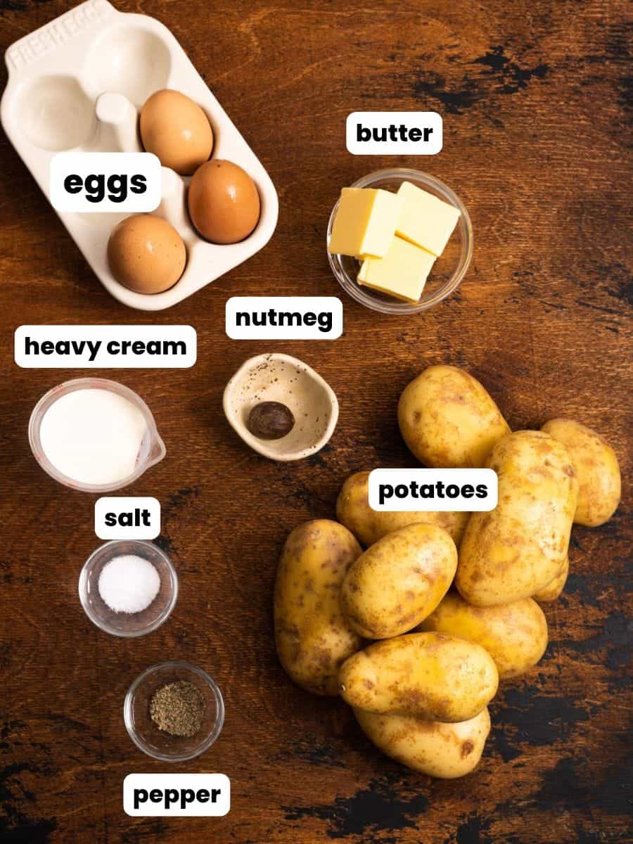 Ingredients for making duchess potatoes in small bowls, arranged on a rustic wooden table.