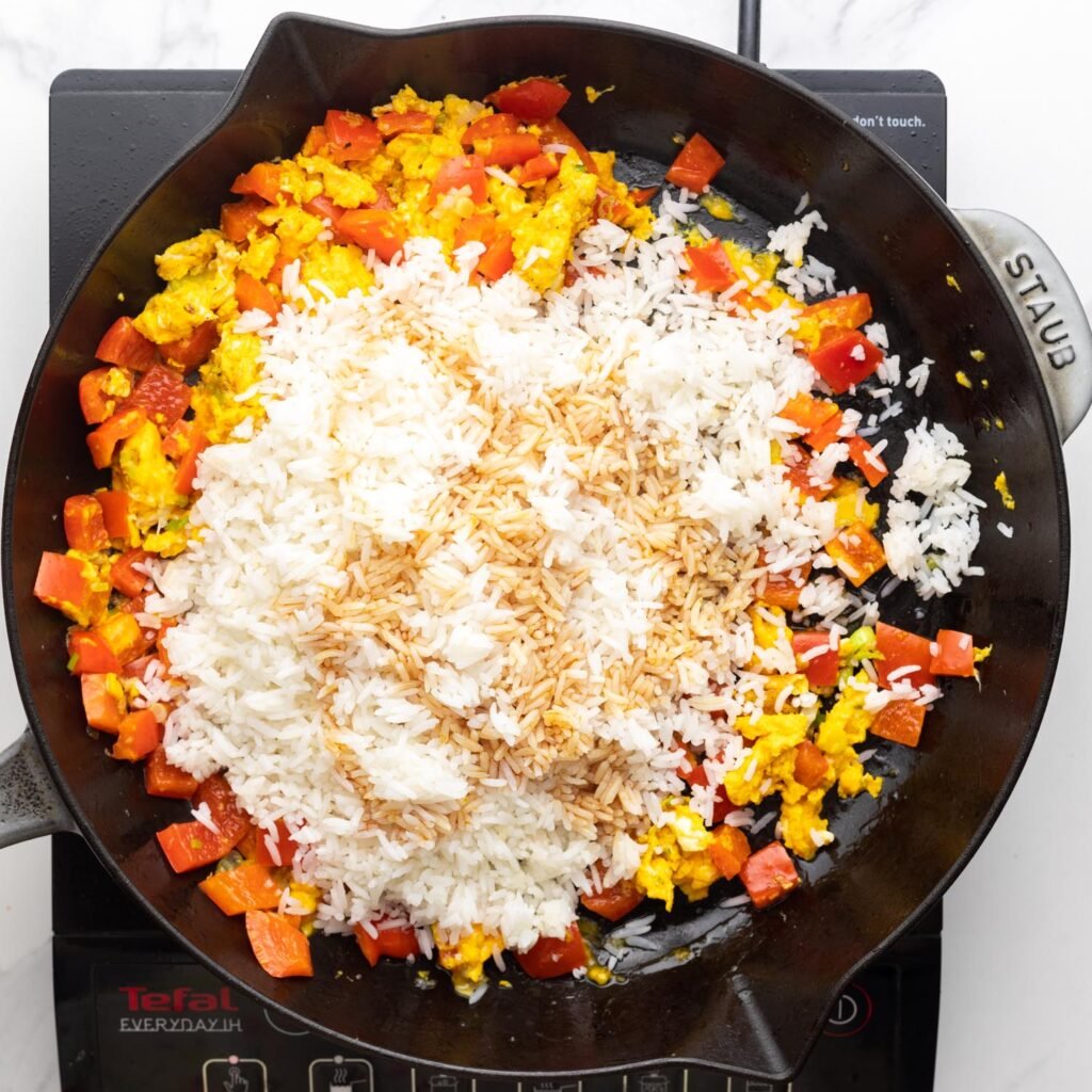 cooked rice added to a skillet with soy sauce to make fried rice.