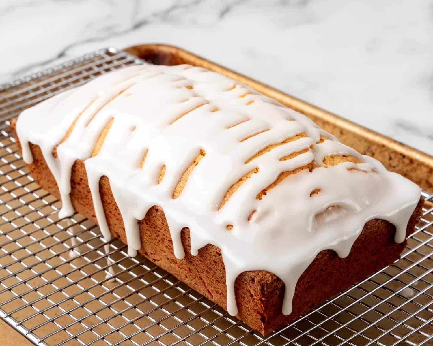 Lemon loaf on a wire rack. Icing has been poured over it. 