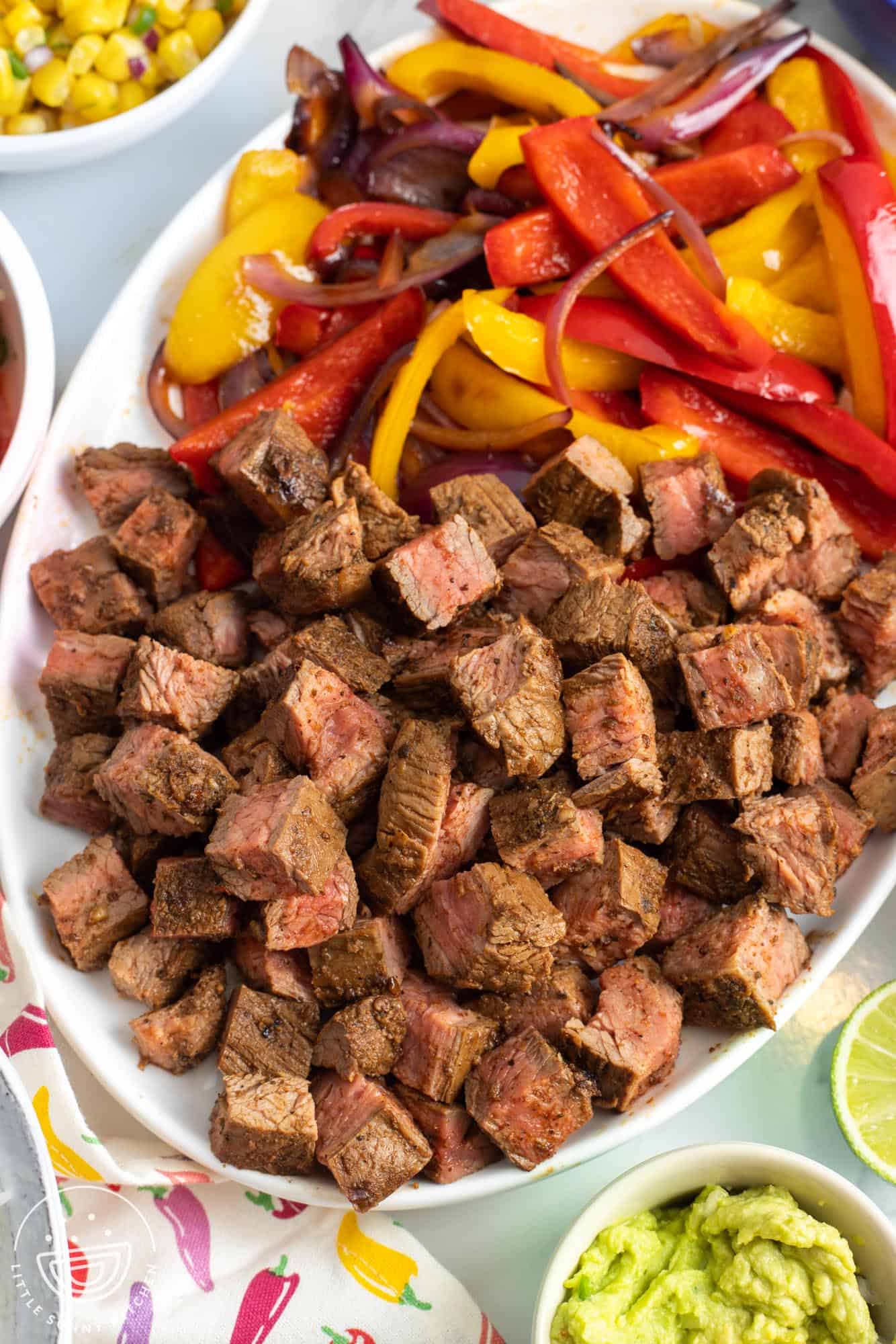 a platter of cubed chipotle steak with sauteed peppers and onions.