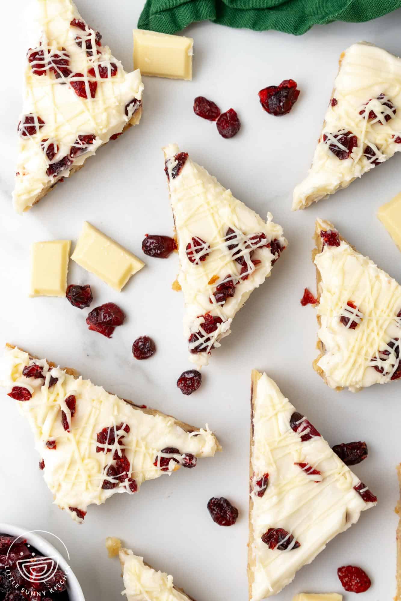 triangular cranberry bliss bars with frosting arranged on a counter.