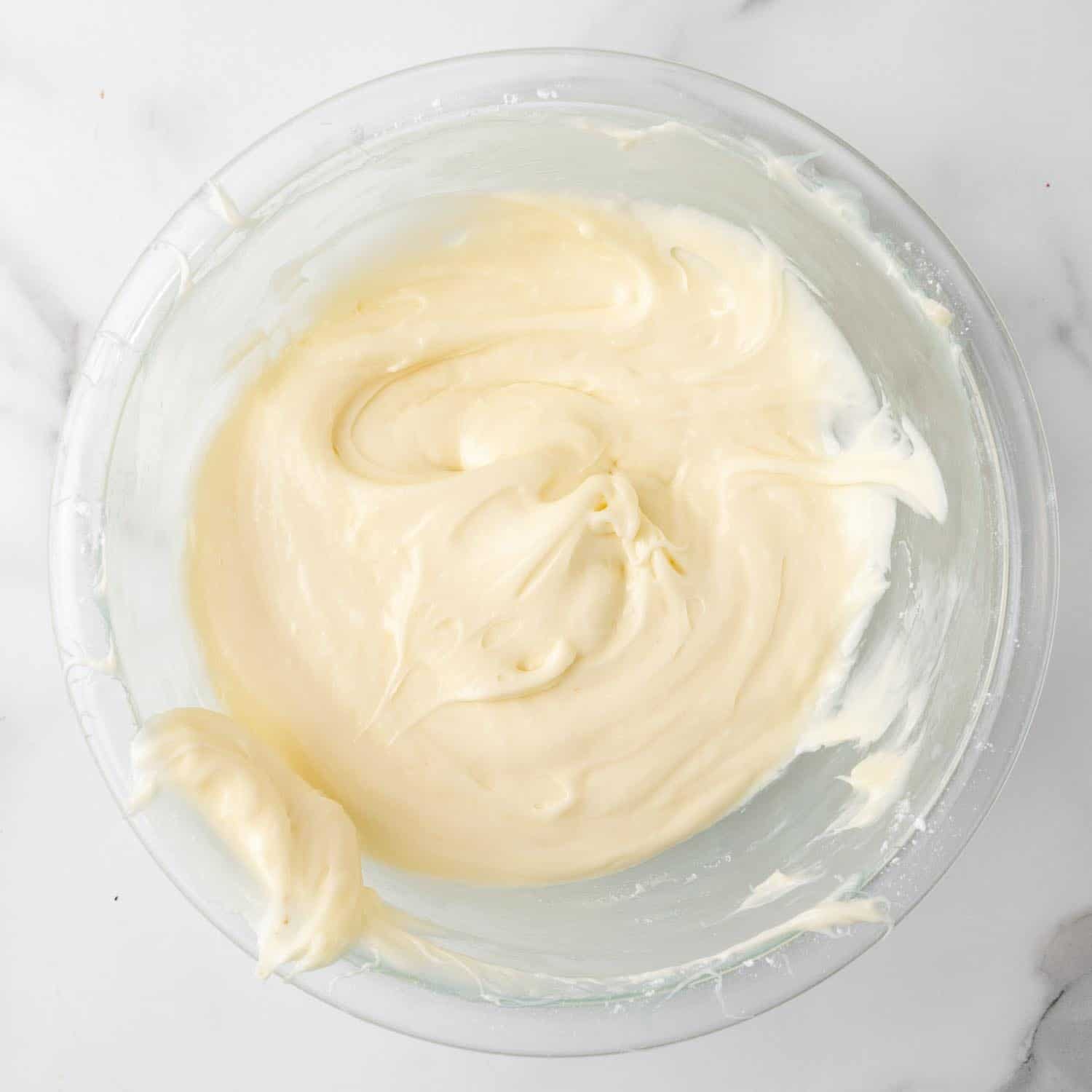 cream cheese frosting for cranberry bars in a glass mixing bowl.